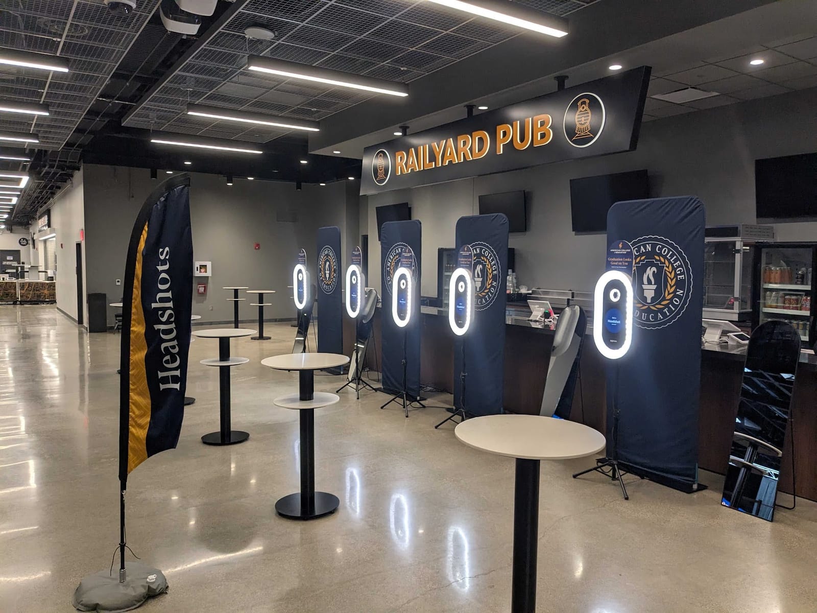 A row of lit Popcam kiosks with American College of Education branding